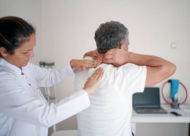 Healthcare worker examining a patient’s neck and shoulders in a clinic room