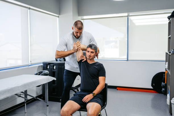 Physical therapist massaging a seated patient’s neck in a bright clinic room