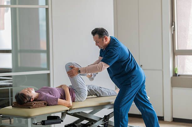 Physical therapist stretching a patient’s leg on a treatment table in a bright clinic room
