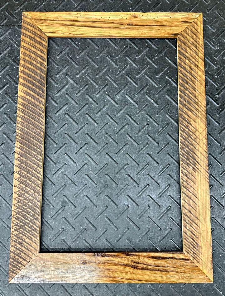 A wooden picture frame is sitting on top of a metal surface.