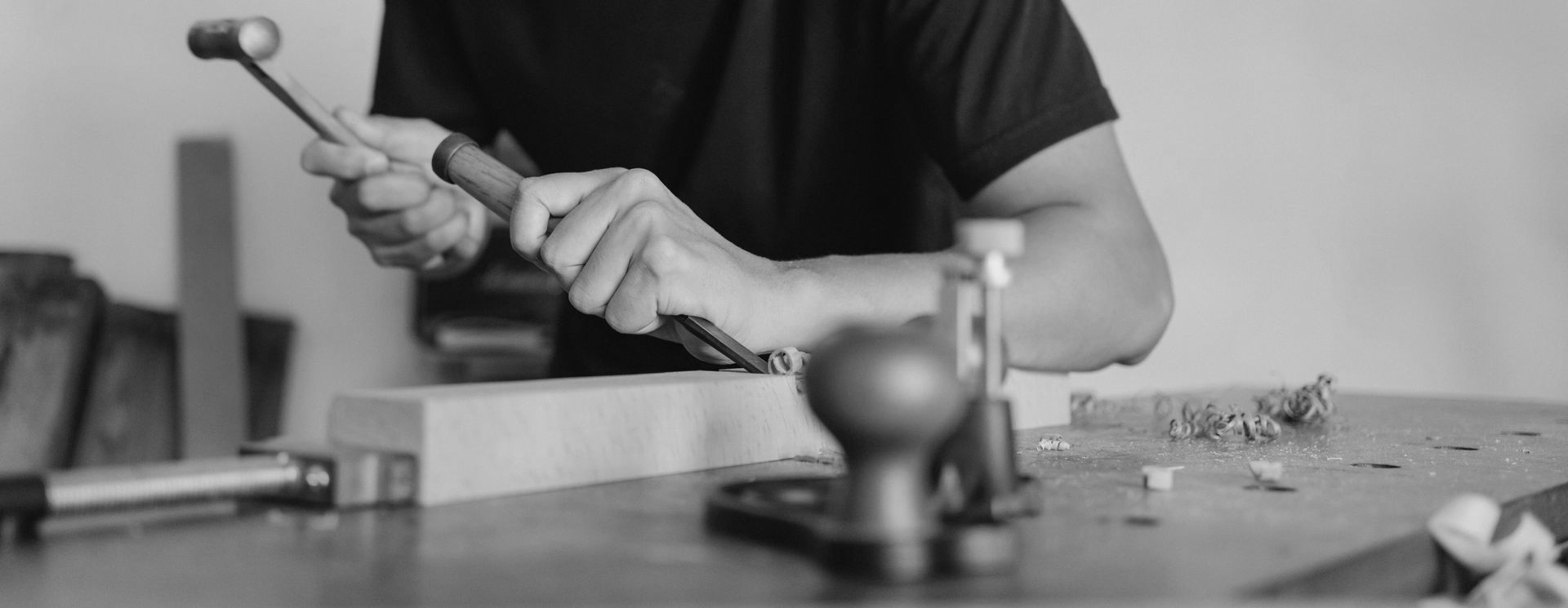 A man is working on a piece of wood with a hammer.