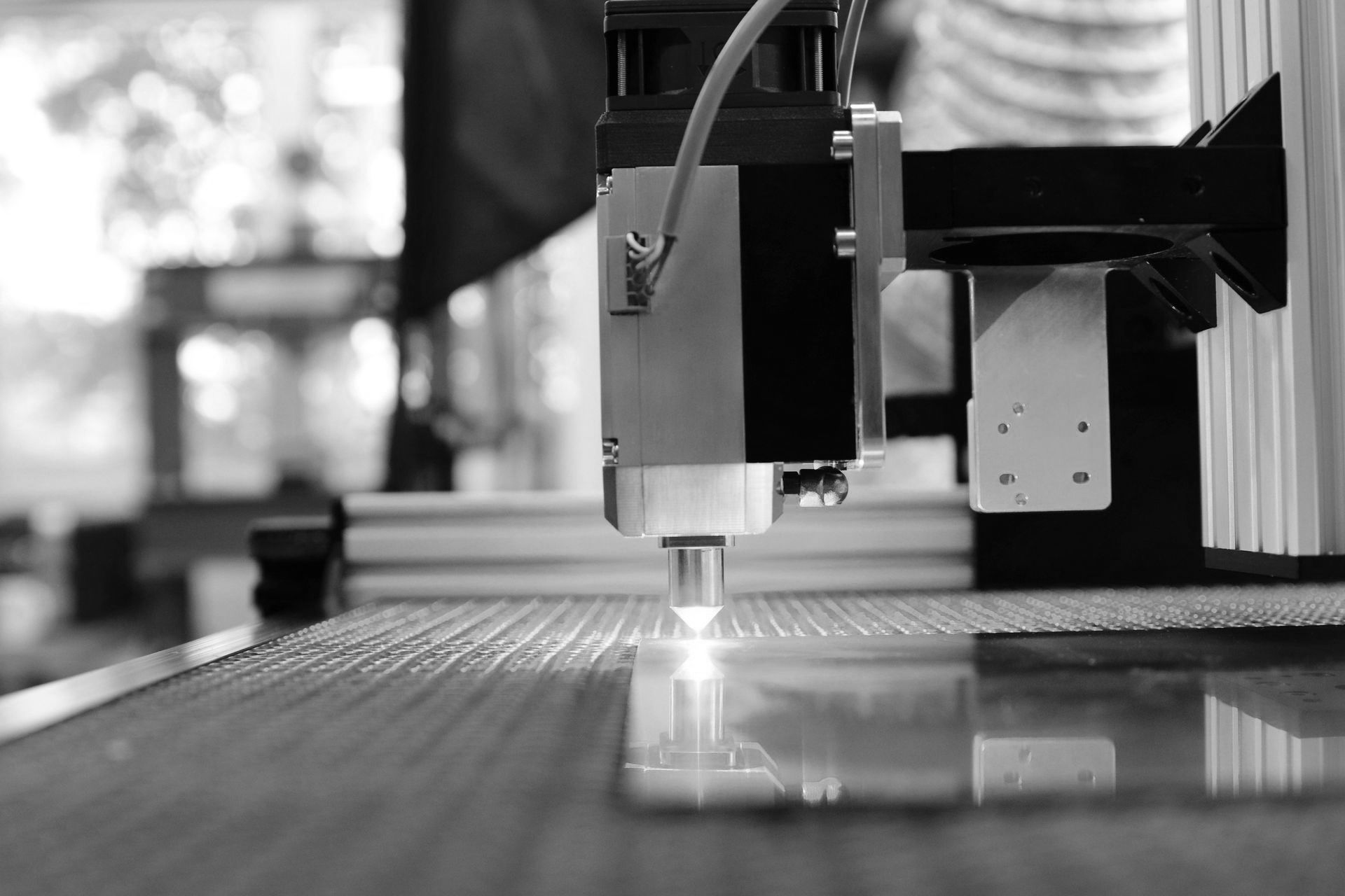A black and white photo of a machine cutting a piece of glass.