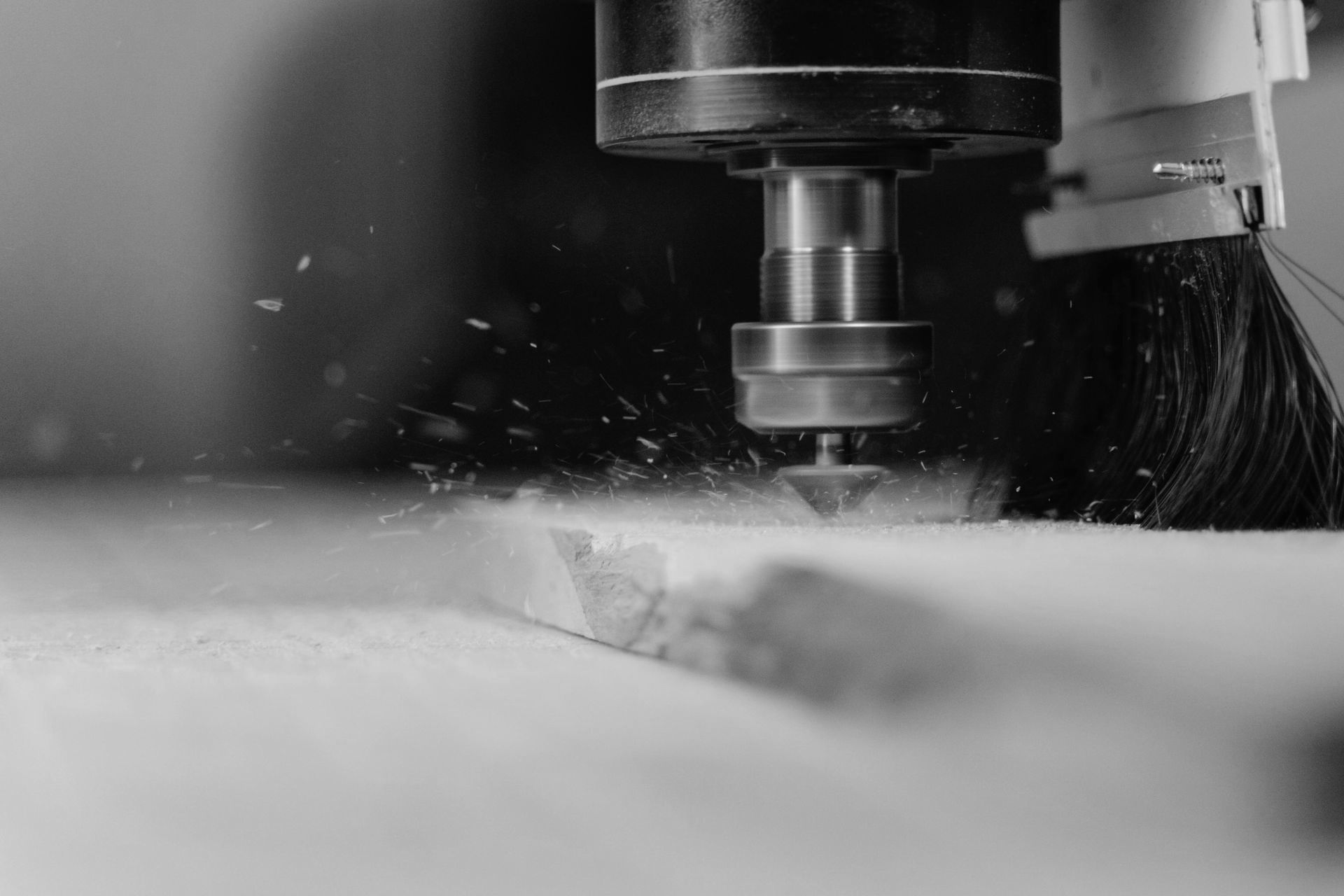 A black and white photo of a machine cutting a piece of wood.