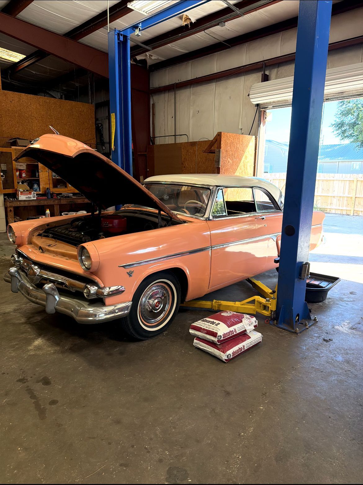 Pink vintage car with open hood on a car lift in ISLAND TRANSMISSION PROS garage.