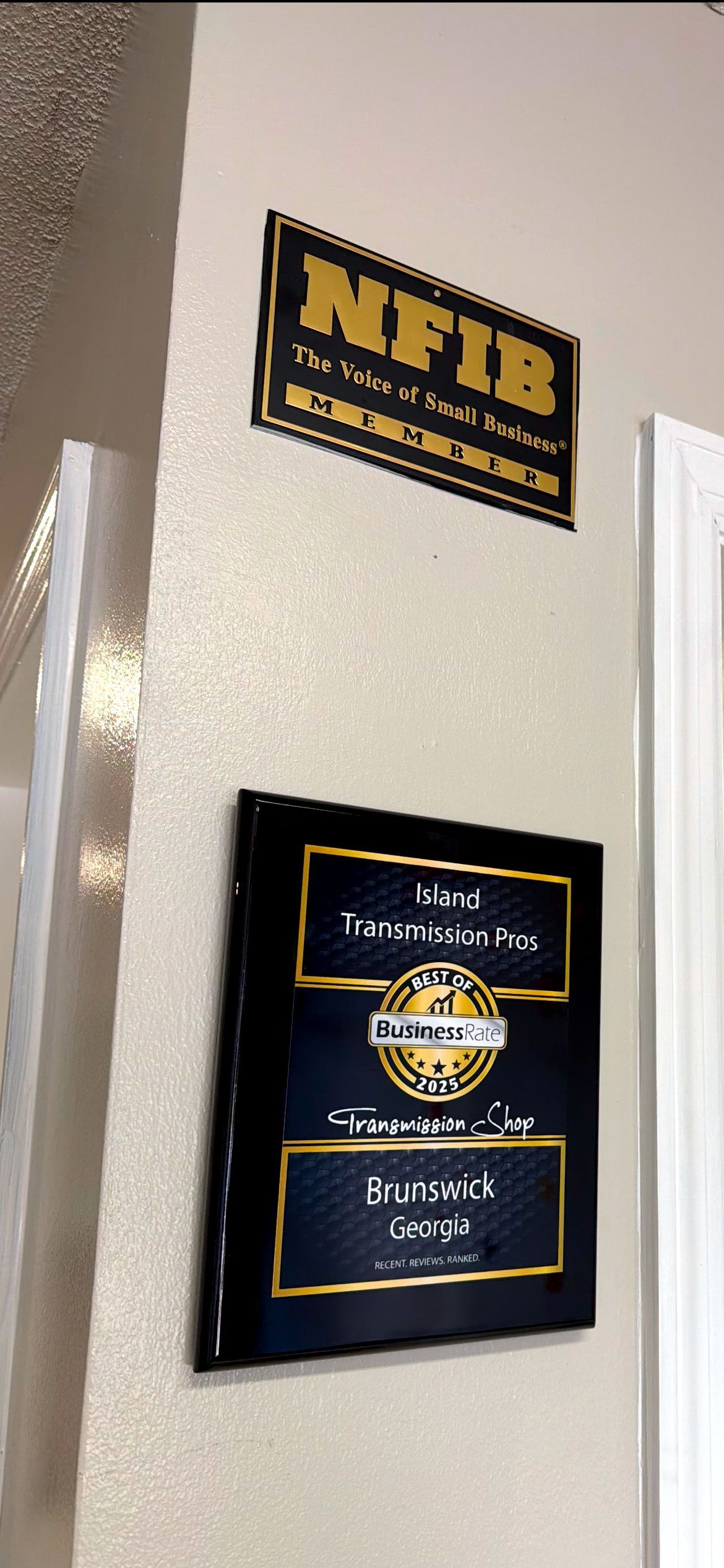Two plaques on a beige wall: NFIB logo above a business award for Island Transmission Inc.