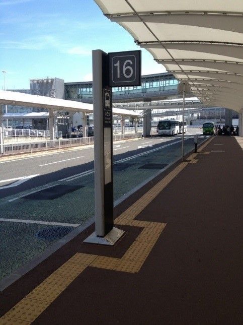 Empty airport platform with gate sign 16 and overhead canopy under a bright sky