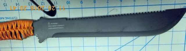 Orange-handled fixed-blade knife with a black sheath, laid on a blue grid background.