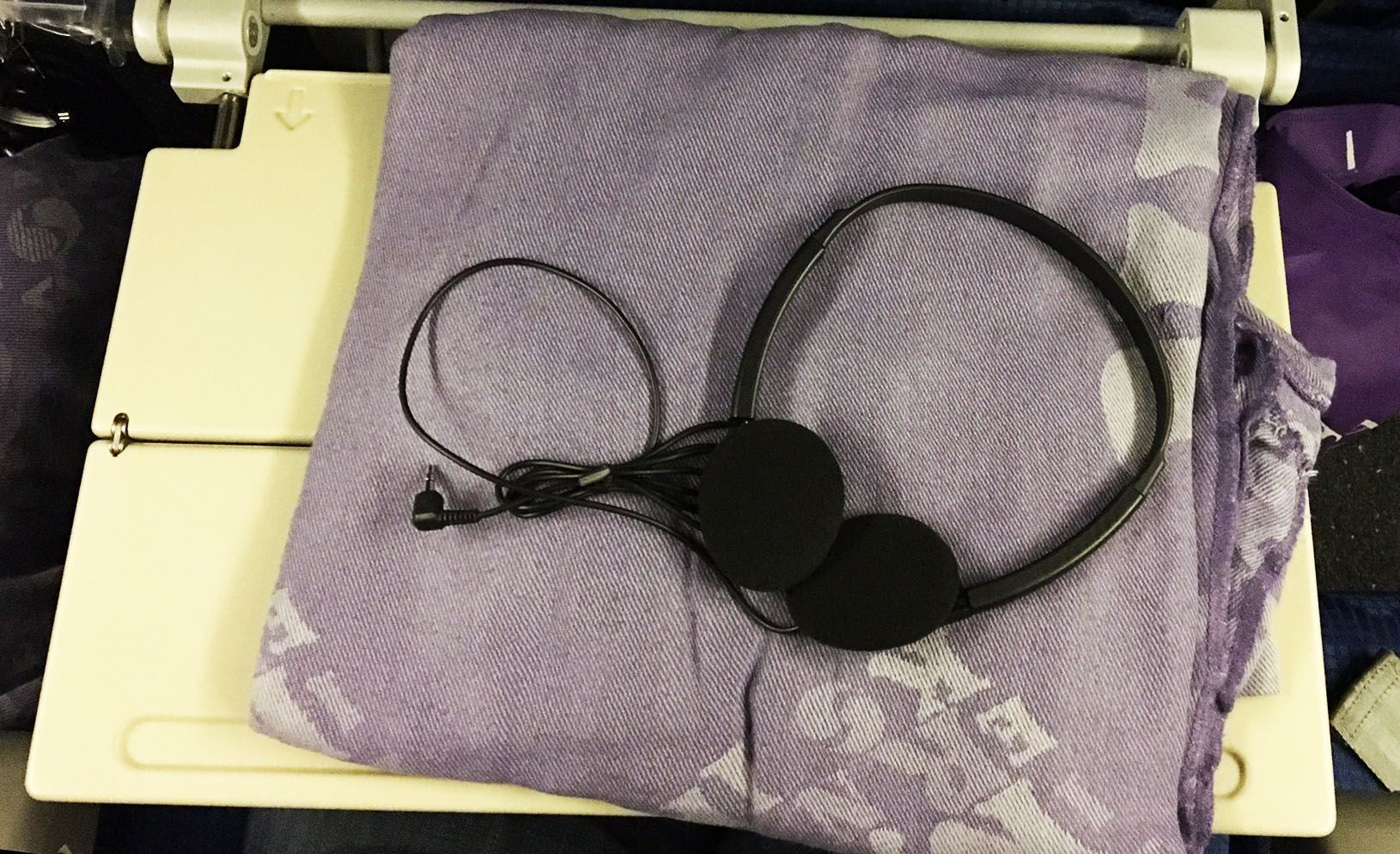 Black headphones resting on a purple cloth over a white keyboard or laptop.