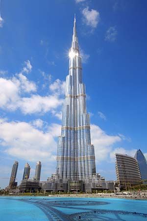 Burj Khalifa rising above a turquoise fountain pool under a bright blue sky