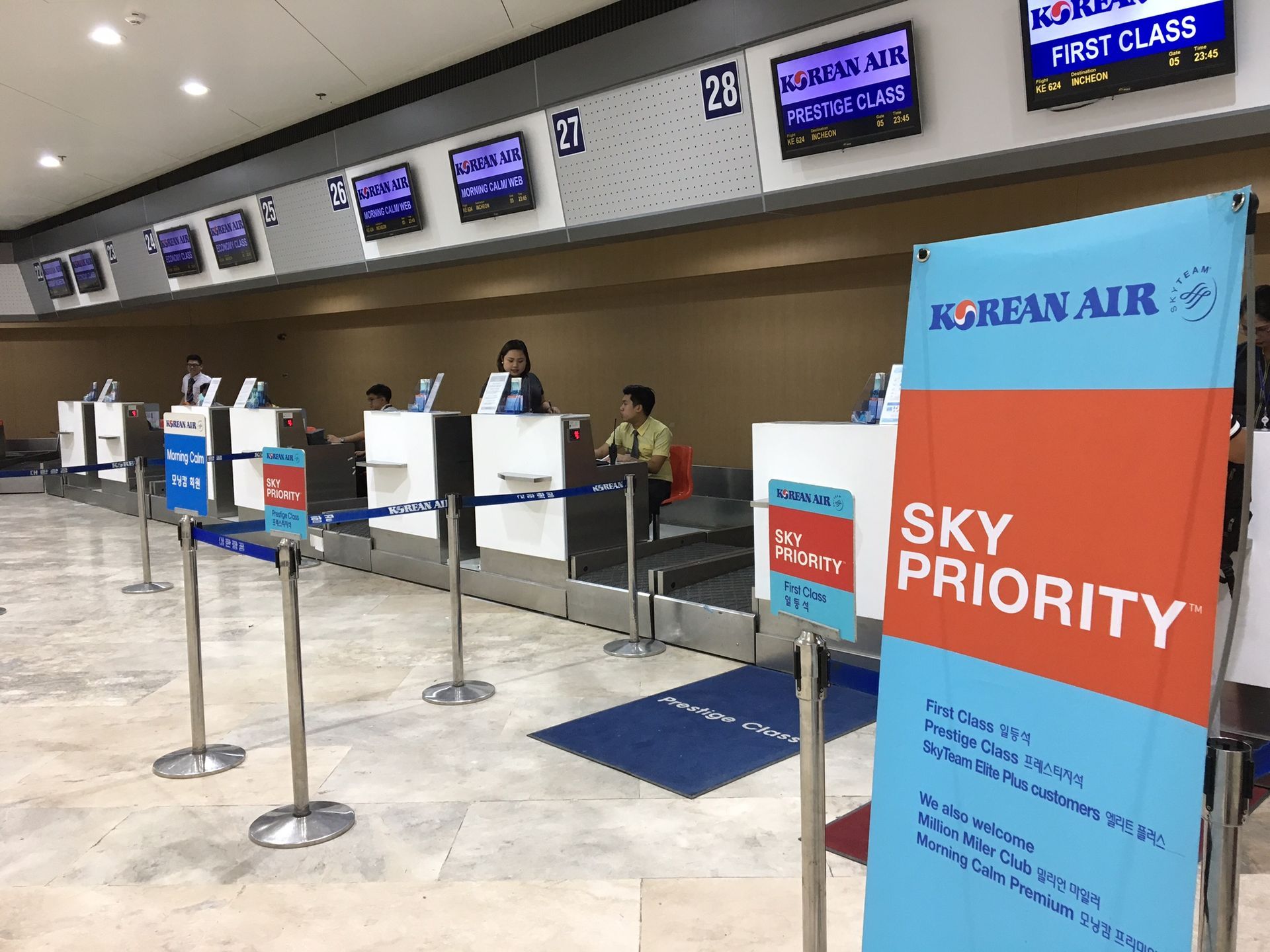 Airport check-in counters with Sky Priority sign and staff behind desks