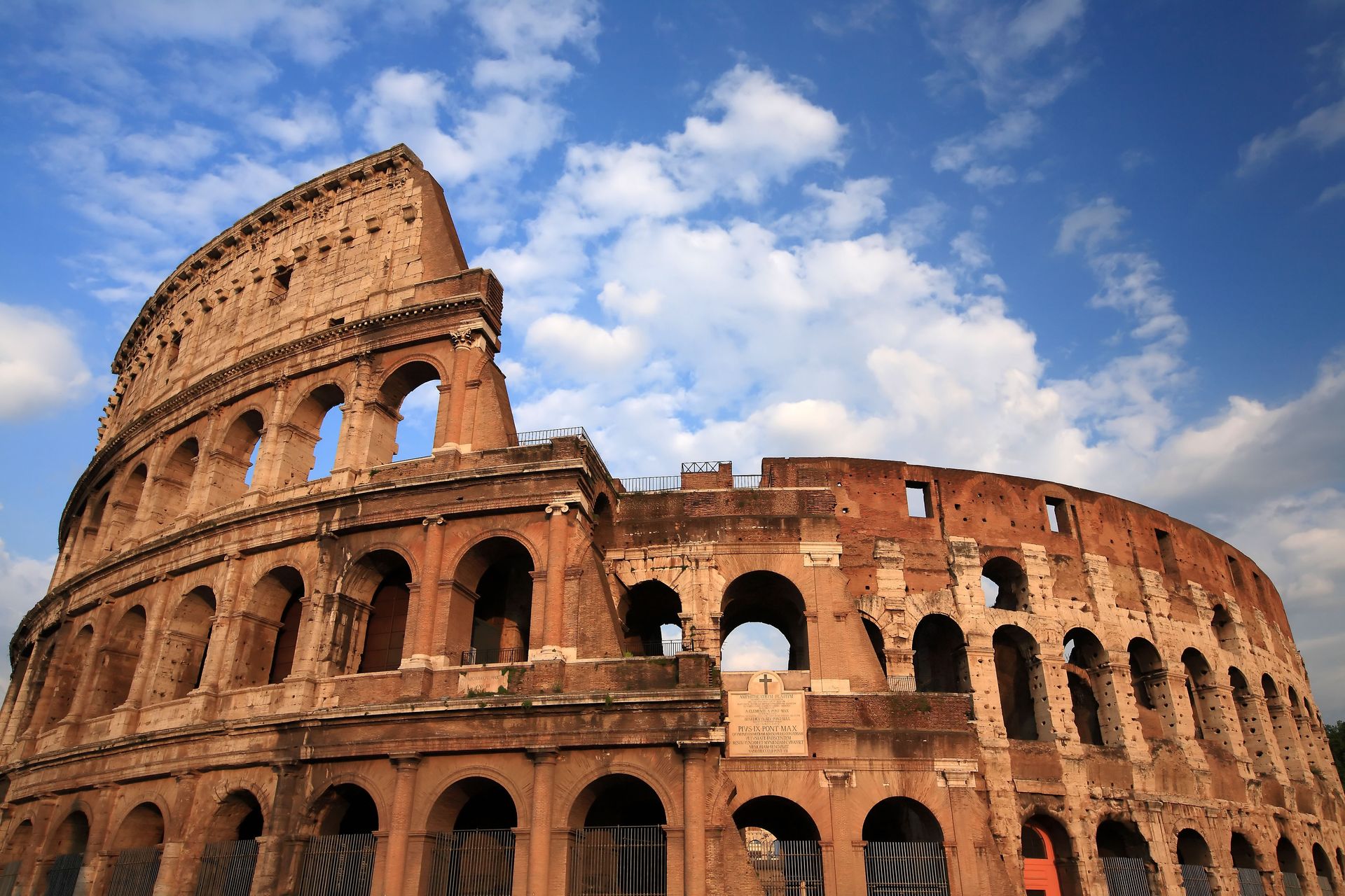 The Colosseum in Rome under a blue sky with scattered clouds.