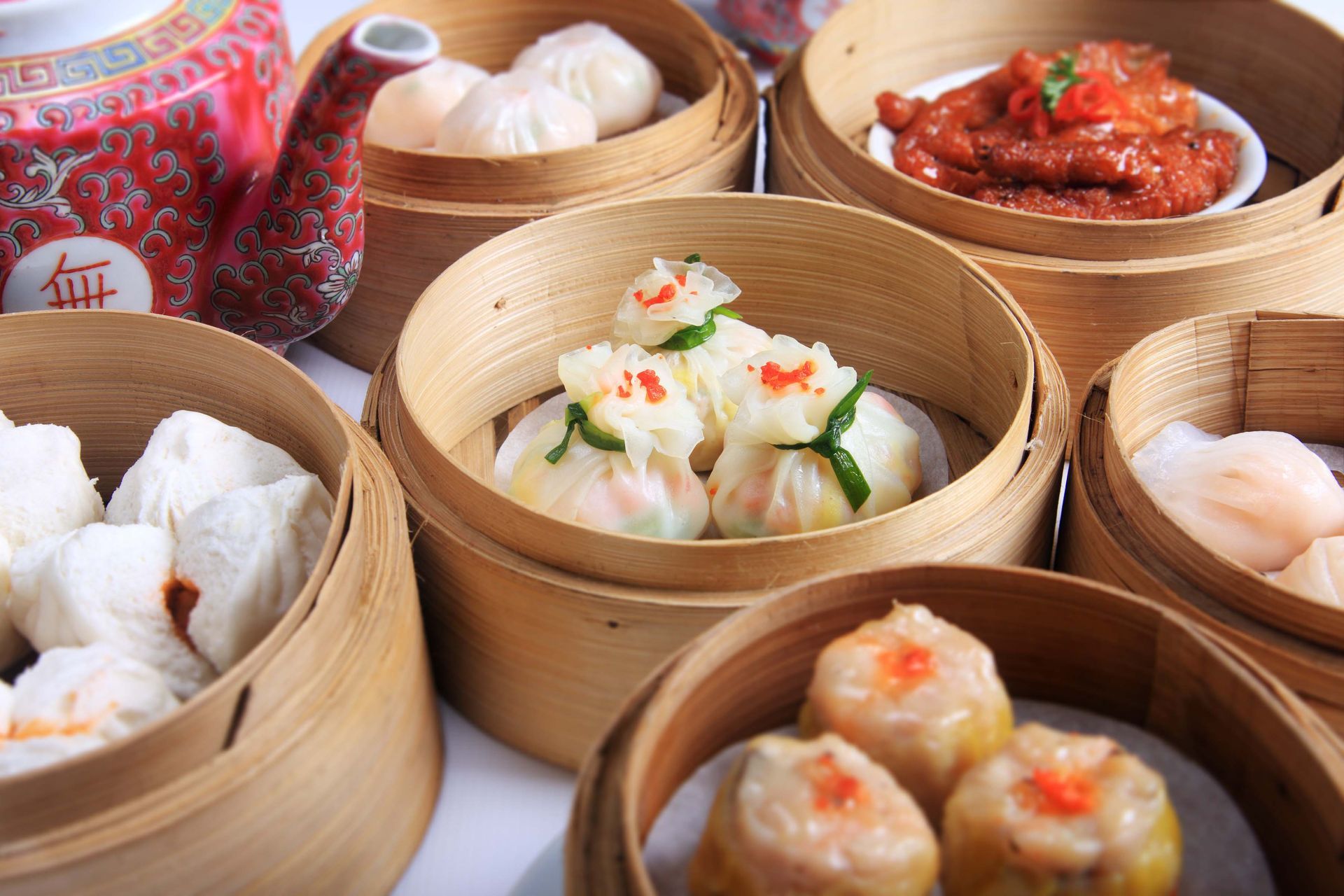 Assorted dim sum in bamboo steamers with dipping sauce on a table