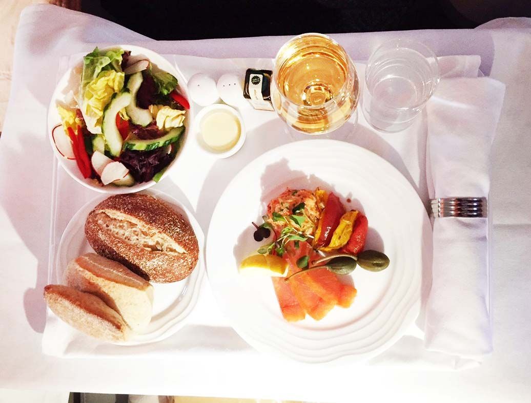 Overhead view of a plated meal with salad, bread, dessert, and drinks on a tray table.