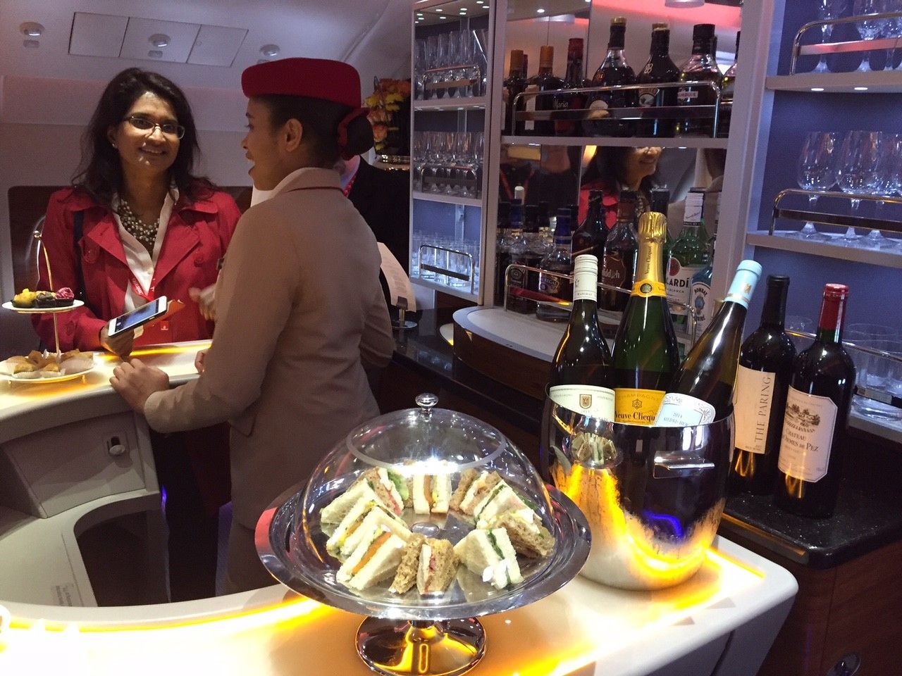 Two people talking at a bar with bottles and champagne on display.