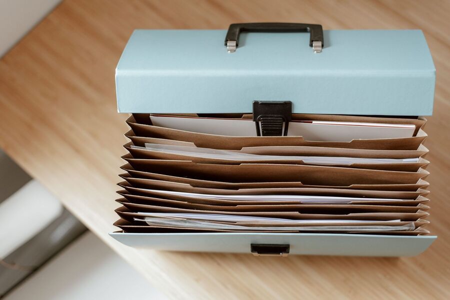 Blue file box with stacked manila folders on a wooden table