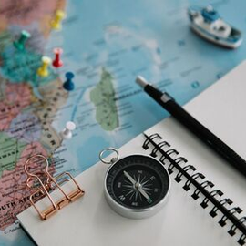 Travel planning flat lay with map, compass, notebook, pen, and paper clips
