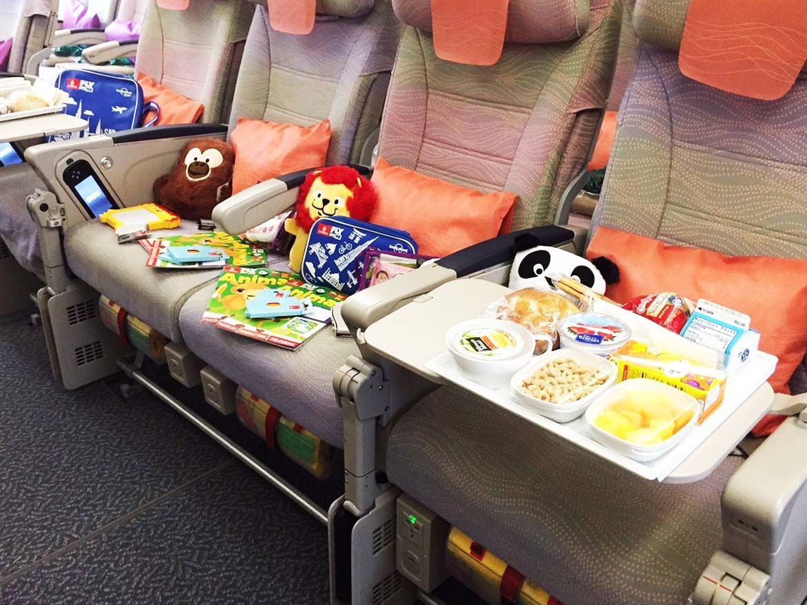 Airplane row with tray tables down, snacks and drinks set out on the seats