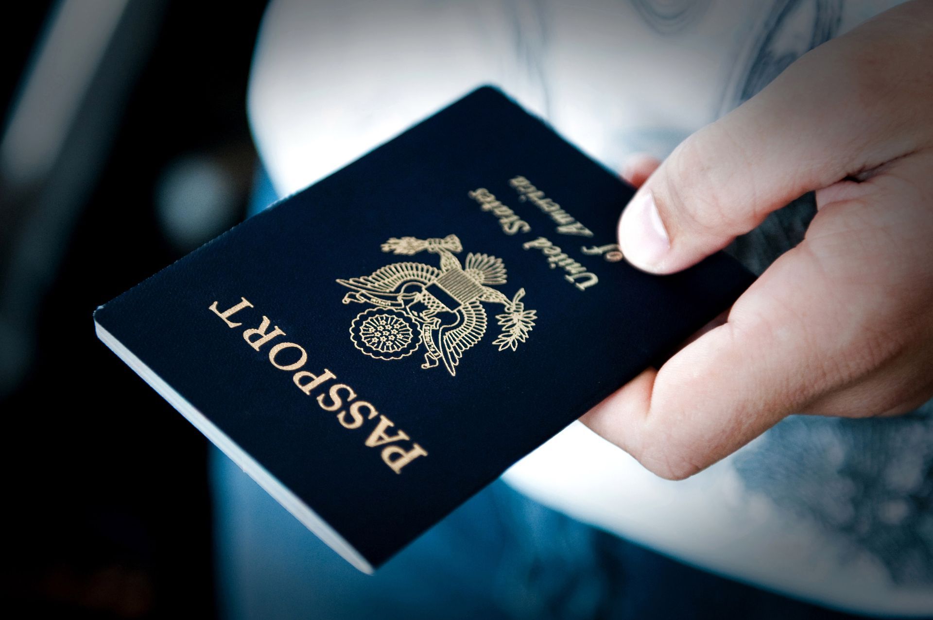 Hand holding a navy passport with gold emblem and text