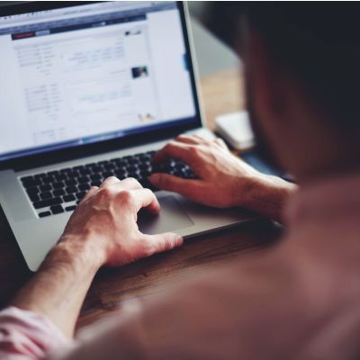 Person typing on a laptop with a blurred webpage on the screen