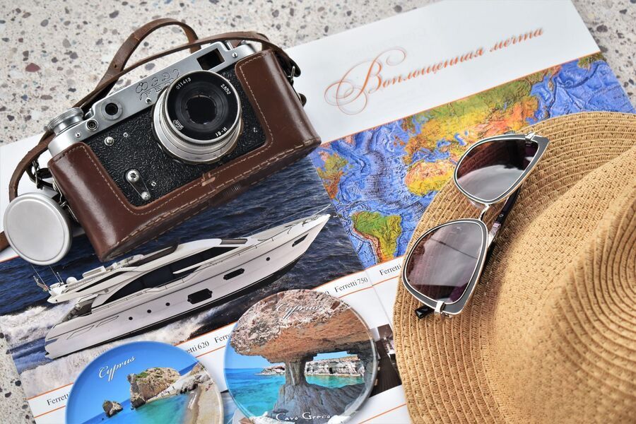 Travel collage with vintage camera, hat, sunglasses, postcards, and nautical decor on a beach-themed background