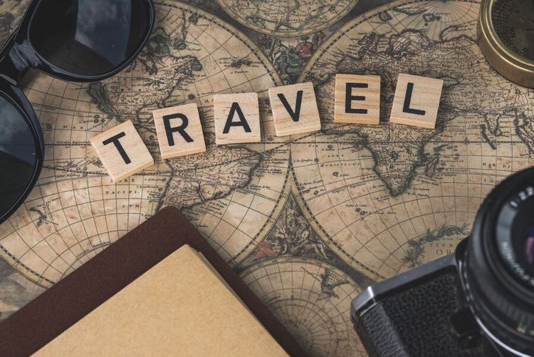 Travel-themed flat lay with camera, world map, compass, flowers, and a passport with boarding pass