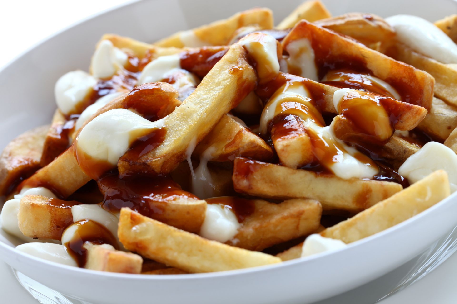 French fries topped with ketchup and white sauce in a white bowl
