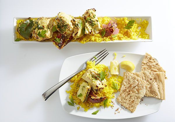 Plated yellow-green salad with pita wedges and fork on a white table setting