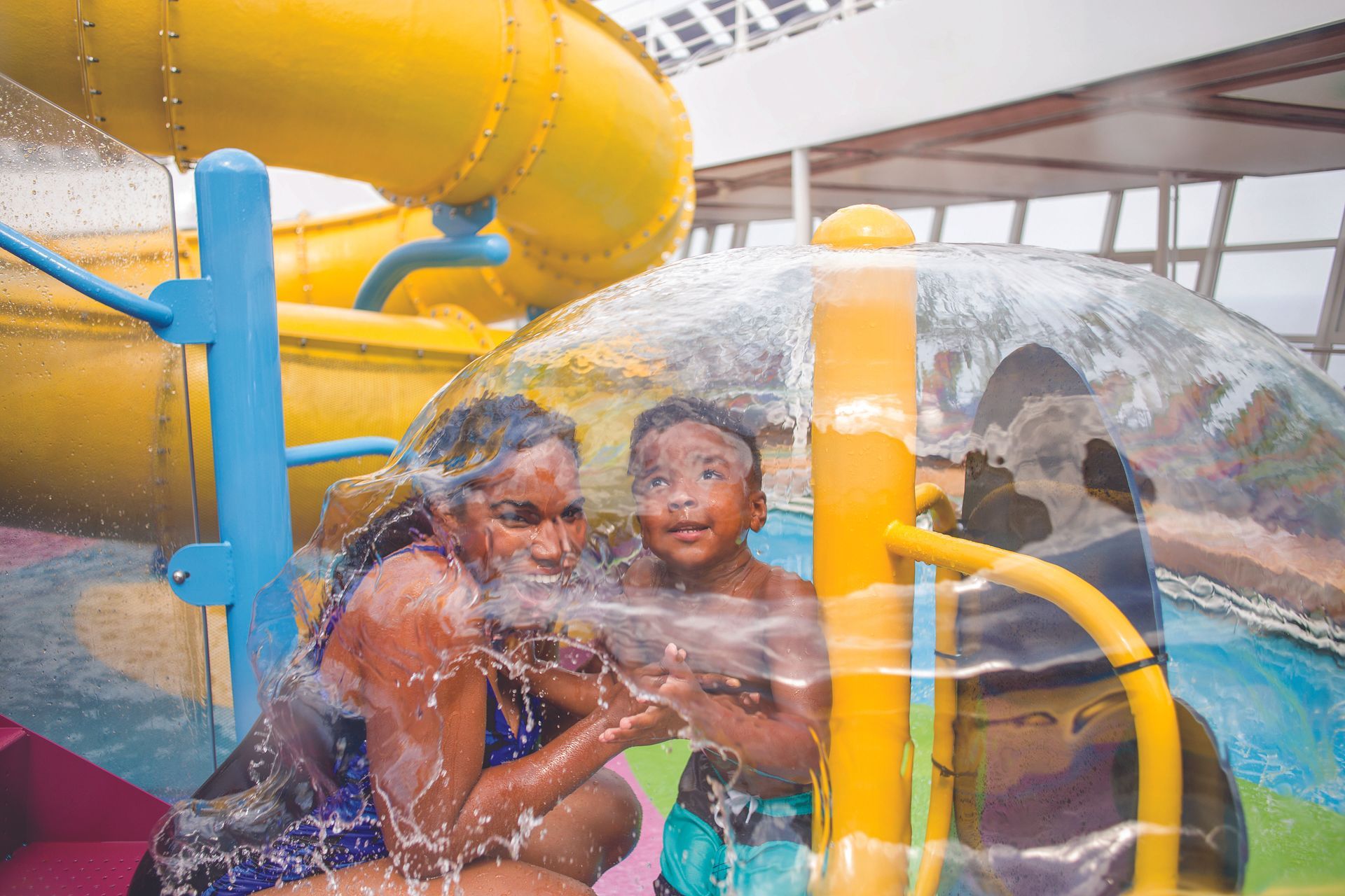 Two children playing in a clear water slide tube at a water park