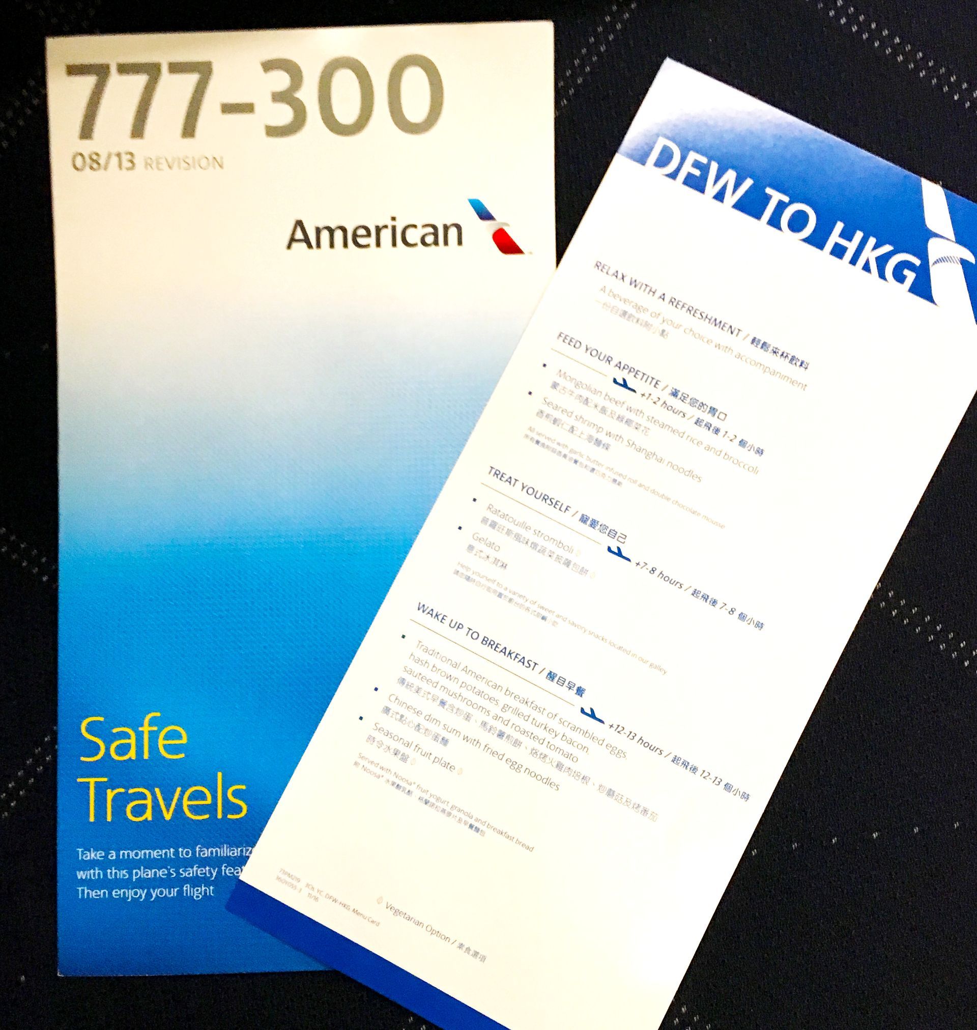 American Airlines 777-300 safety card and white form on a dark seatback pocket