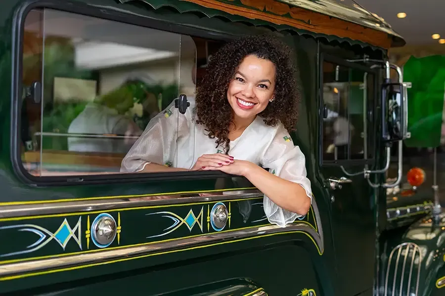 Smiling woman leaning out of a green vintage truck window in a garage