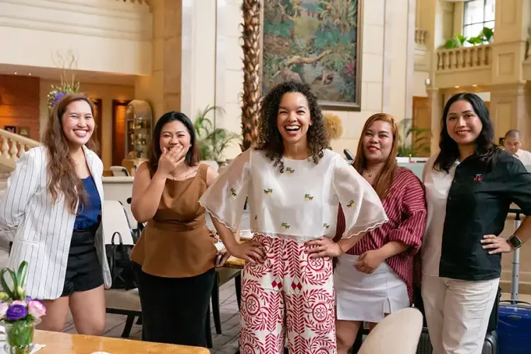 Five people smiling and posing together in a bright, ornate room