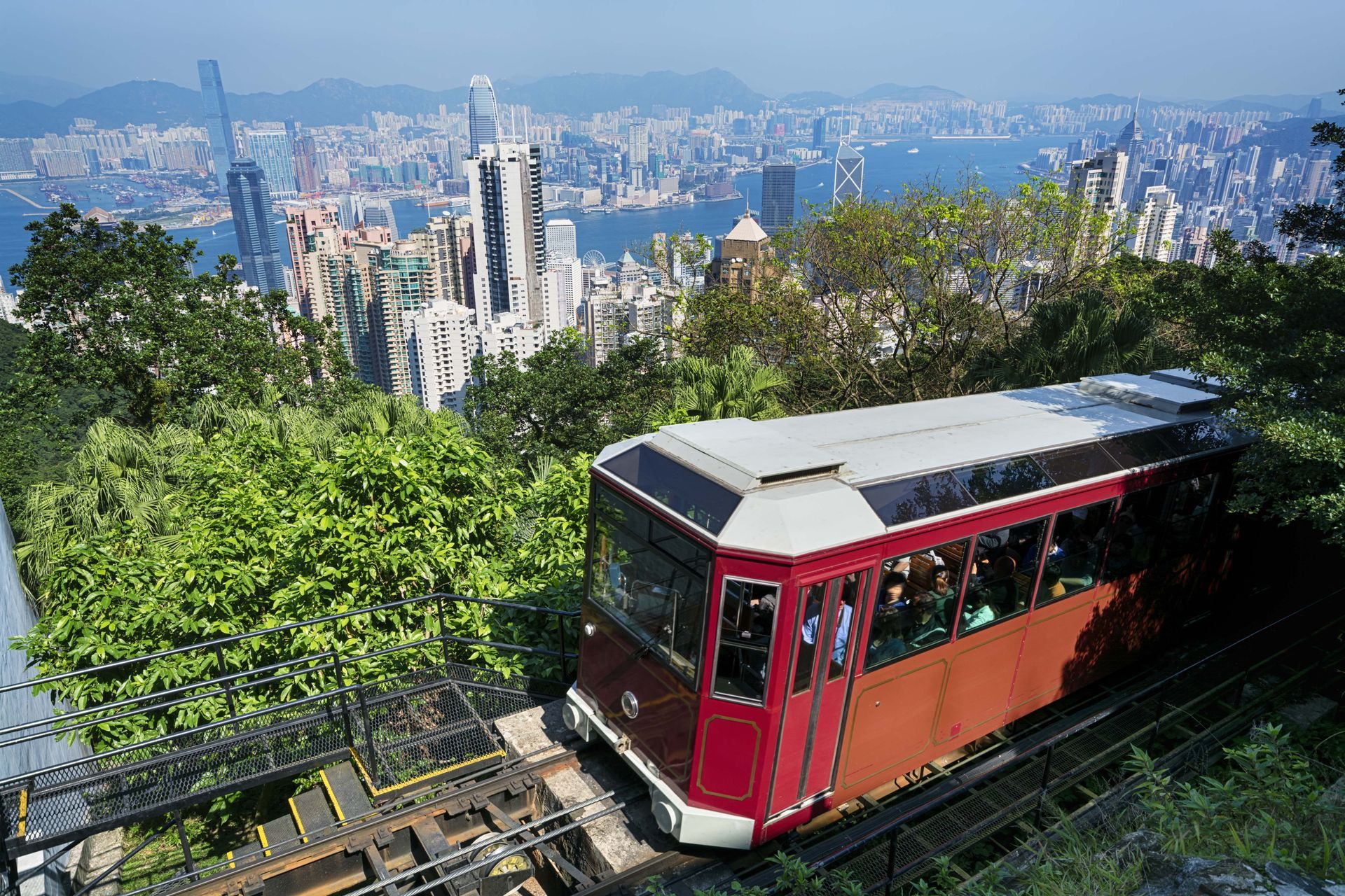 Red funicular climbing a hillside above a city skyline on a sunny day
