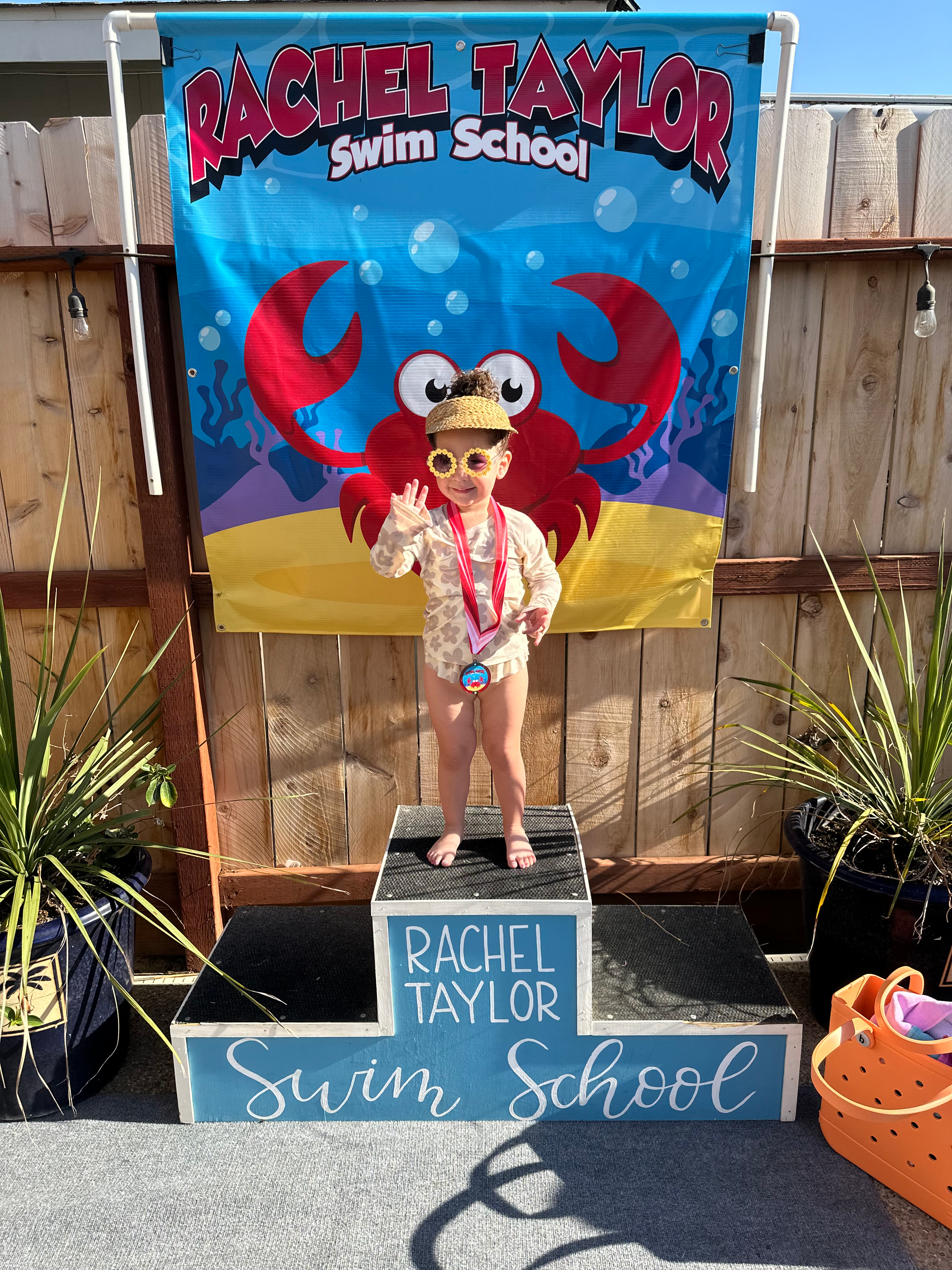 A young child in swimwear and sunglasses stands on a 