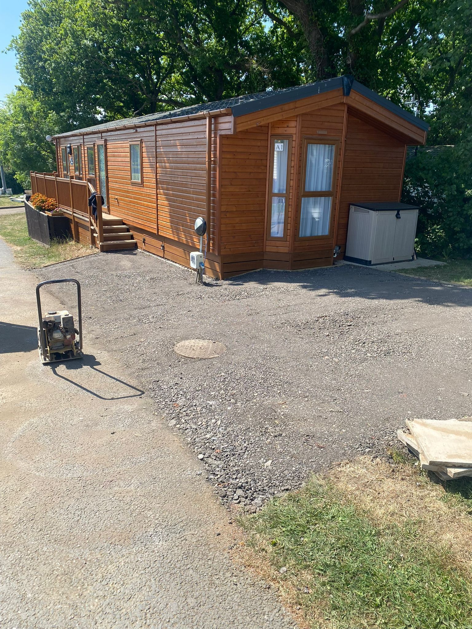 Wooden cabin with steps, gravel driveway, portable generator, and a hot tub. Outdoors.