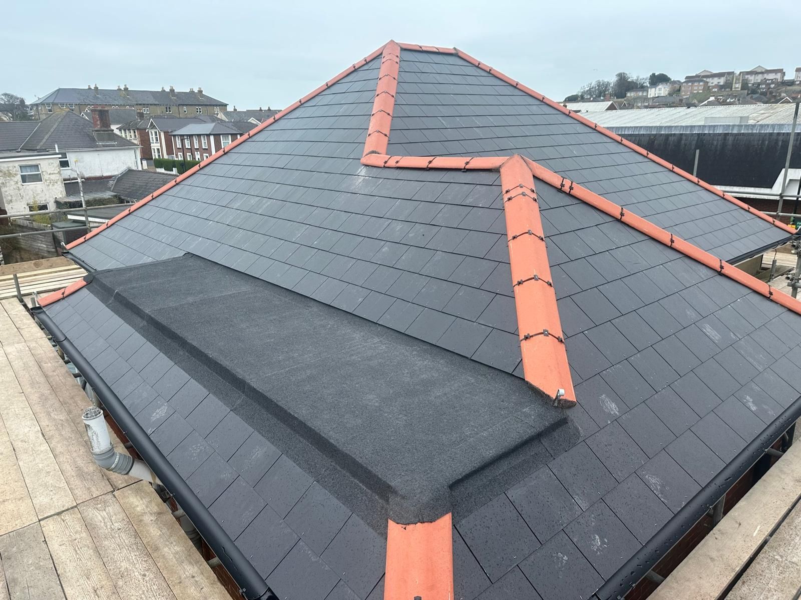 A pyramid shaped roof with black tiles and red trim