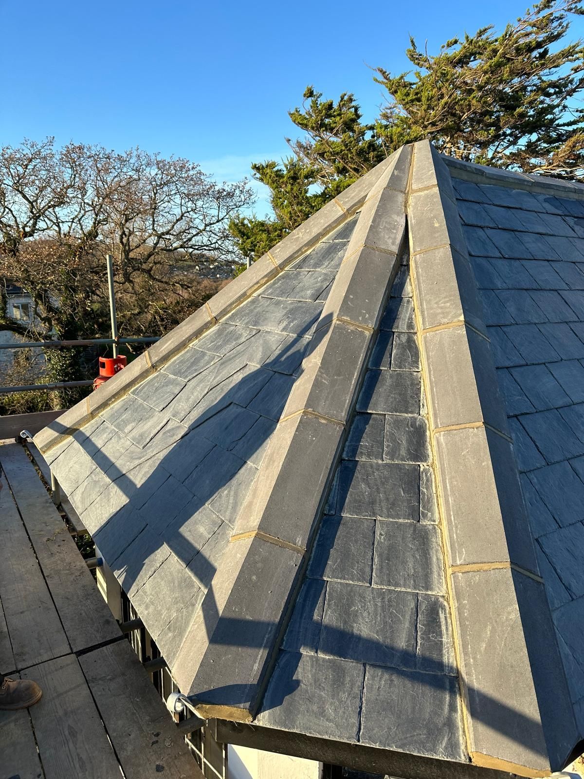 A roof with a pyramid shaped roof and a blue sky in the background.