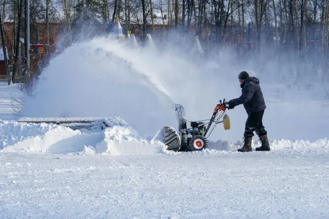 Man clearing deep snow with a snow blower.