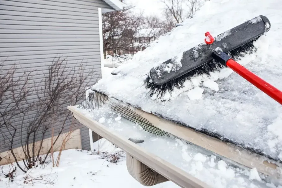 Brushing snow and ice off a residential roof.