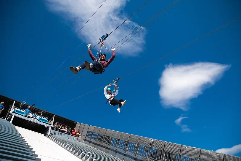 To personer flyr gjennom luften på en zip-line.