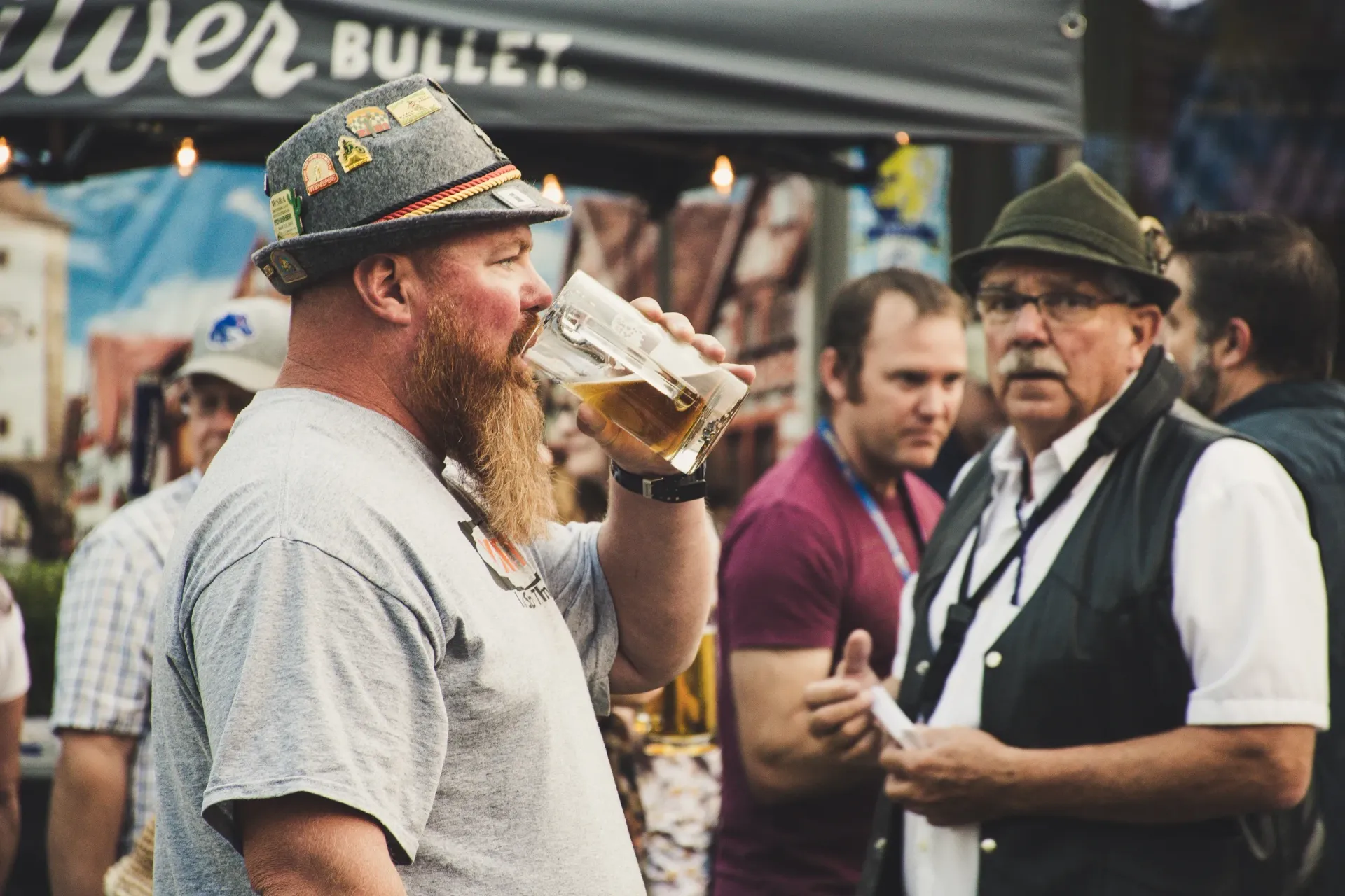 En mann med skjegg drikker en øl på en ølfestival.