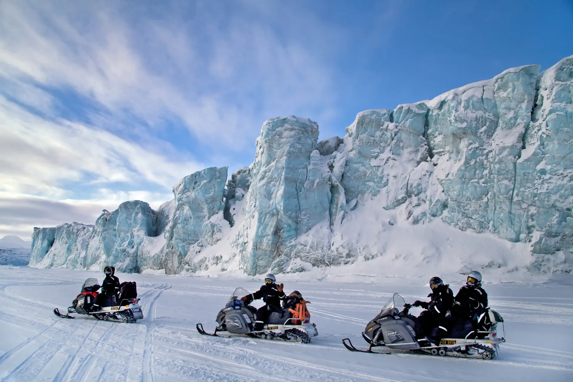 En gruppe mennesker kjører snøscooter i snøen.