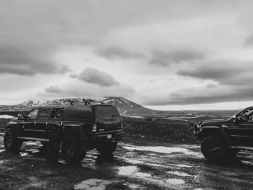 Et svart-hvitt bilde av to jeeper parkert på en grusvei.