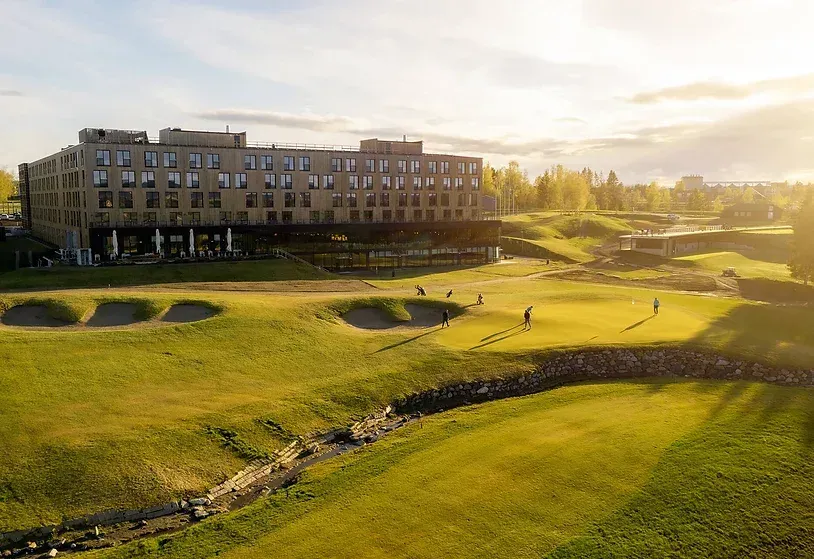 Et luftfoto av en golfbane med en stor bygning i bakgrunnen.