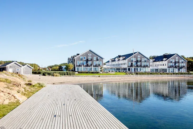 En brygge som fører til en innsjø med en husrekke i bakgrunnen