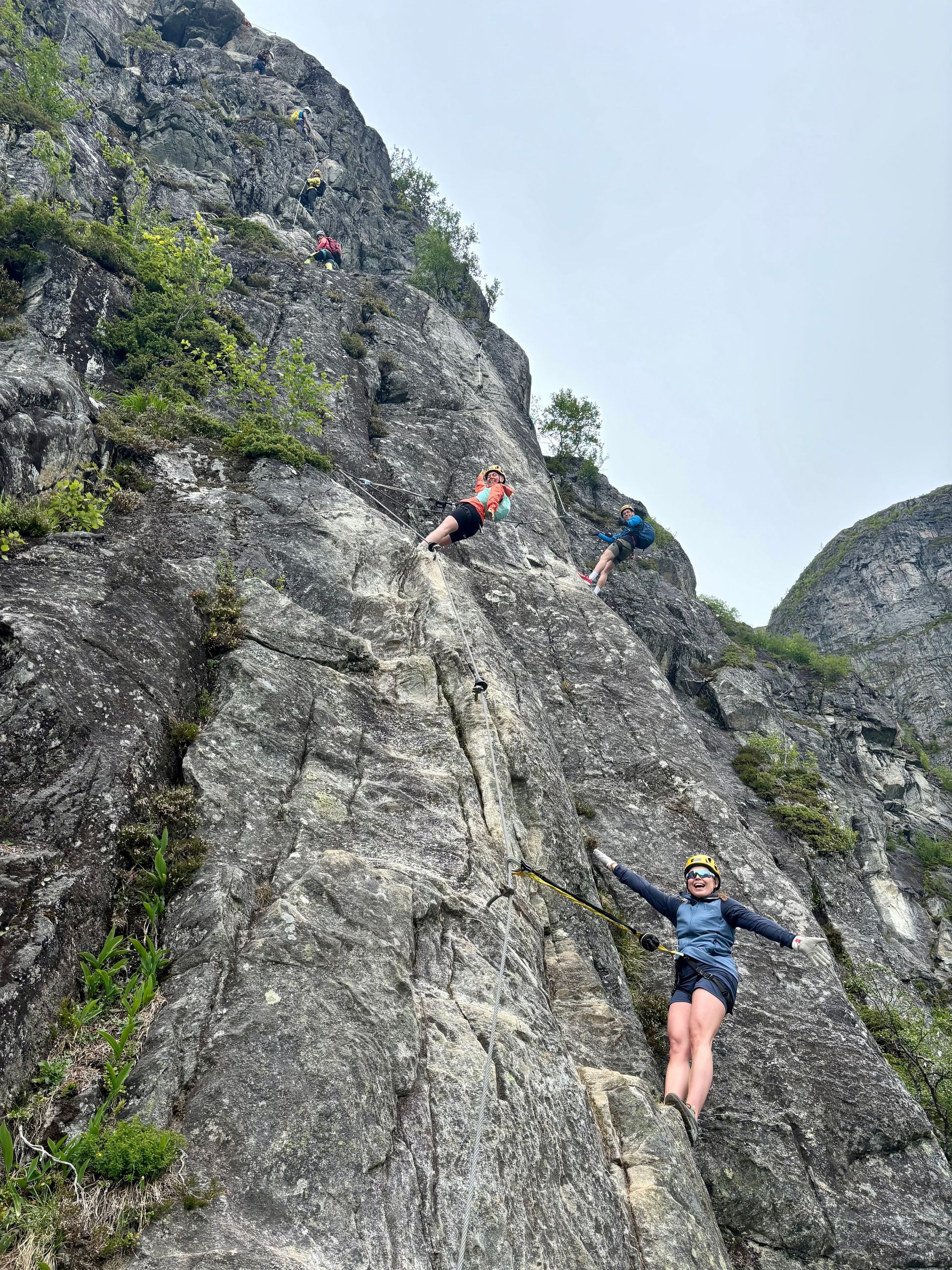 En gruppe mennesker klatrer opp en steinete klippe.
