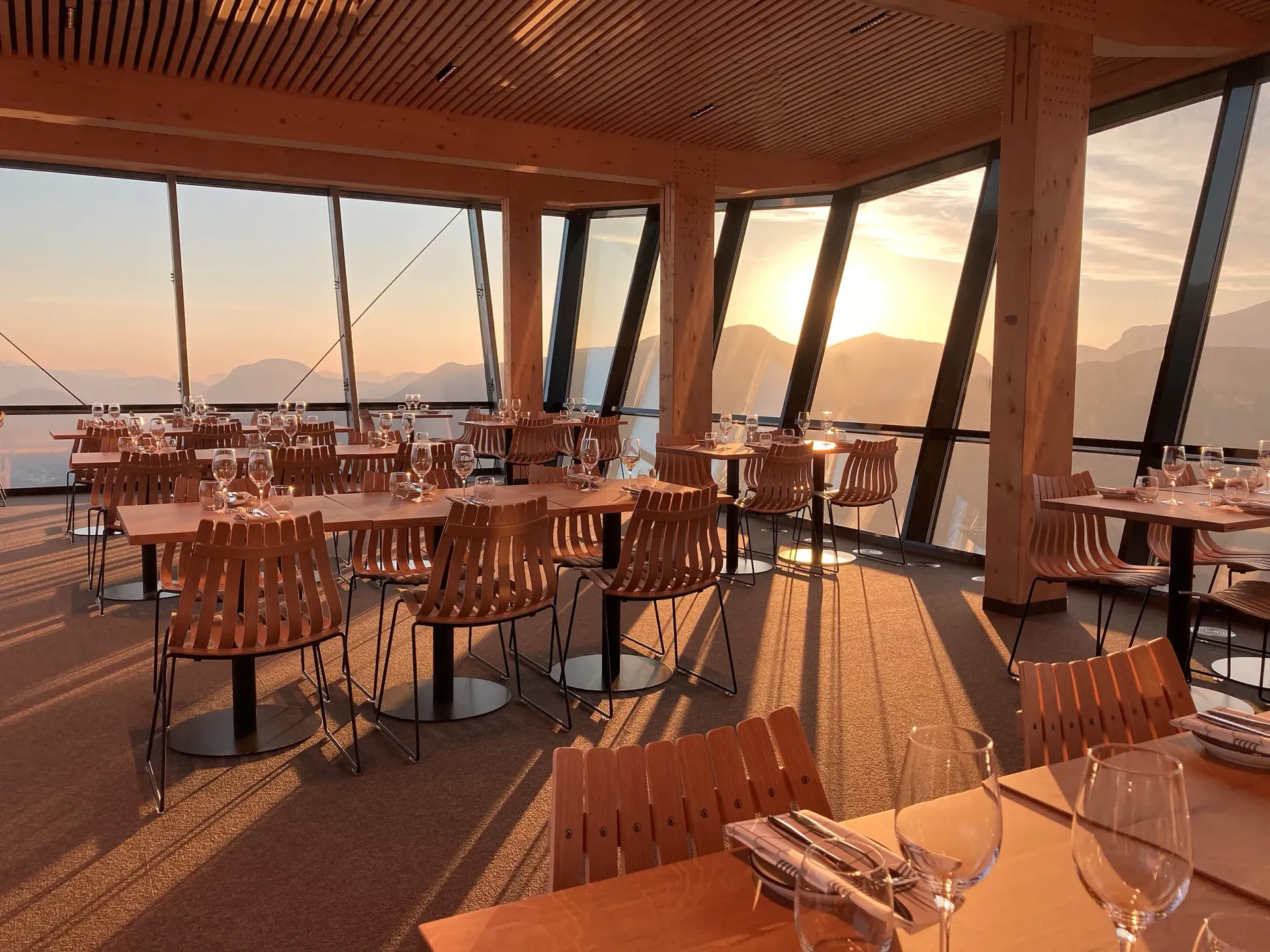 En restaurant med bord og stoler og utsikt over solnedgangen.