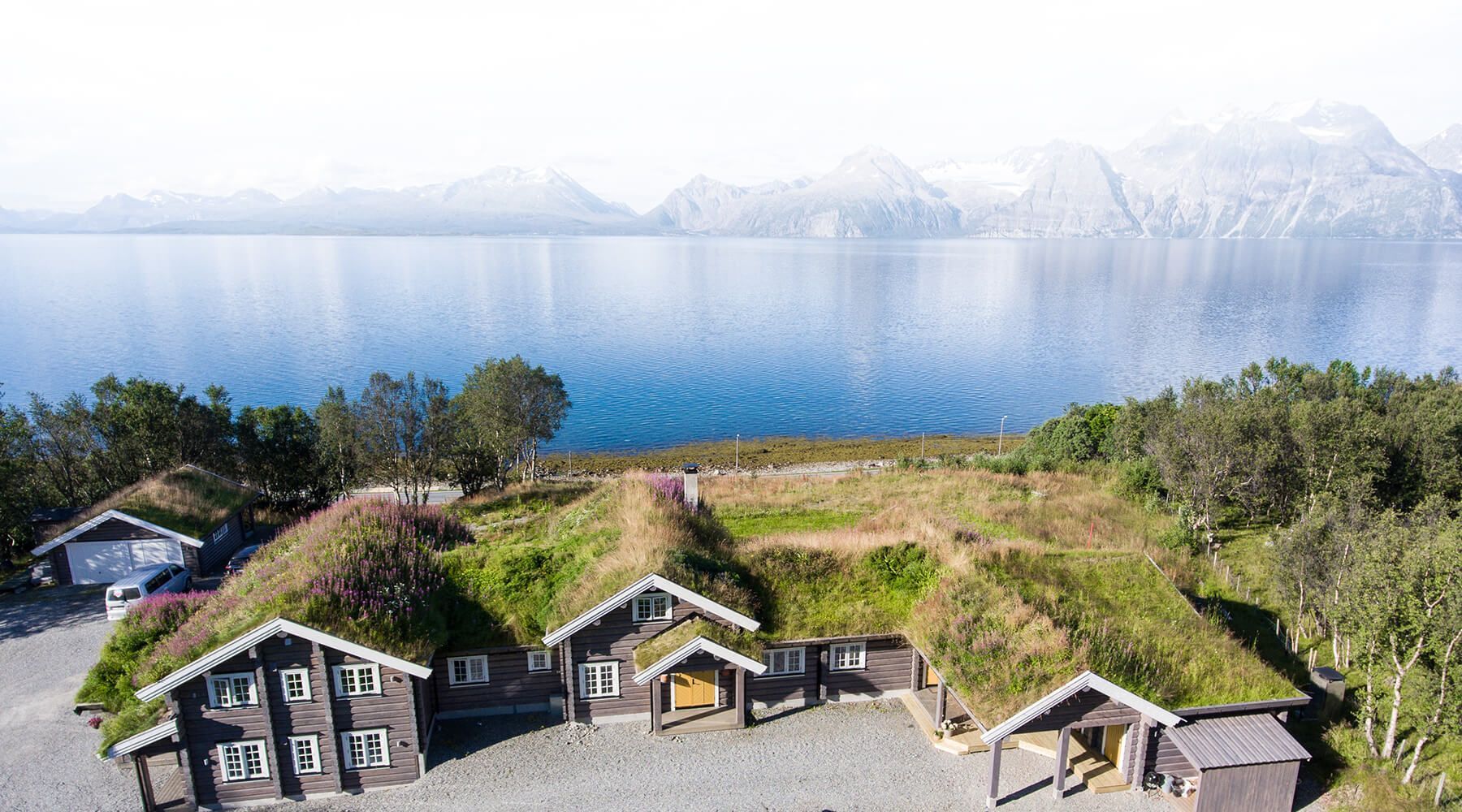 En gruppe hus som sitter på toppen av en høyde ved siden av en innsjø.