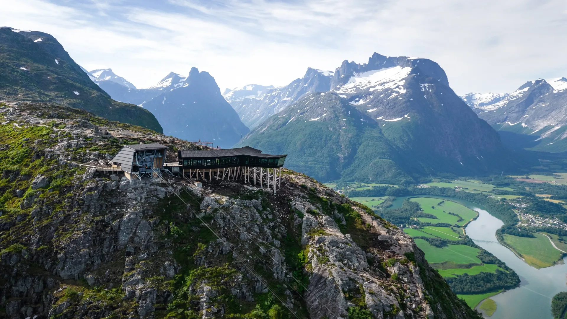 En luftfoto av en bygning på toppen av et fjell omgitt av fjell og en elv.