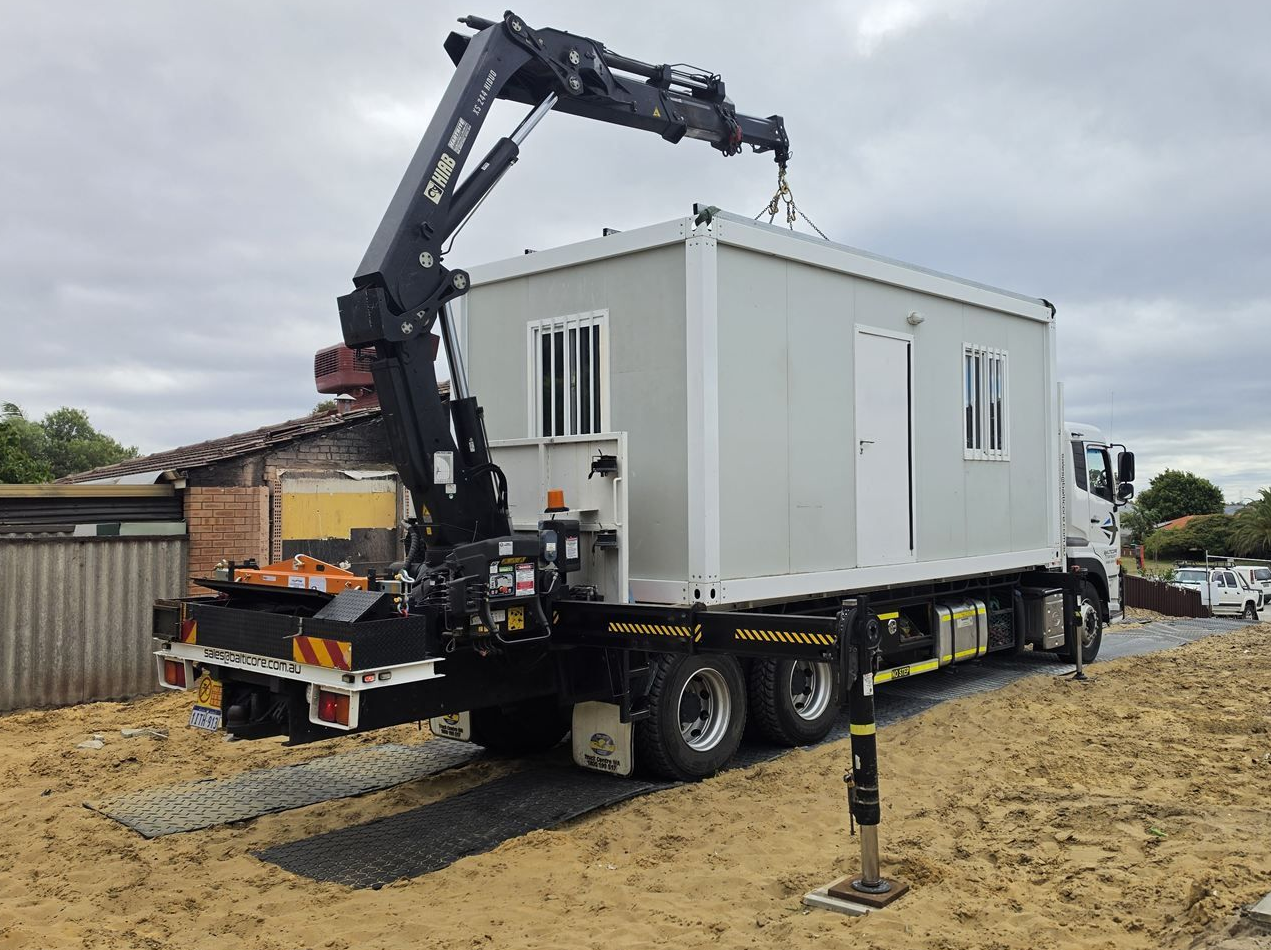 Balticore Hiab crane lifting a site office onto the truck