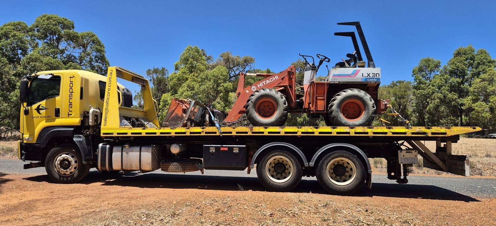Balticore tilt tray truck carrying a wheel loader